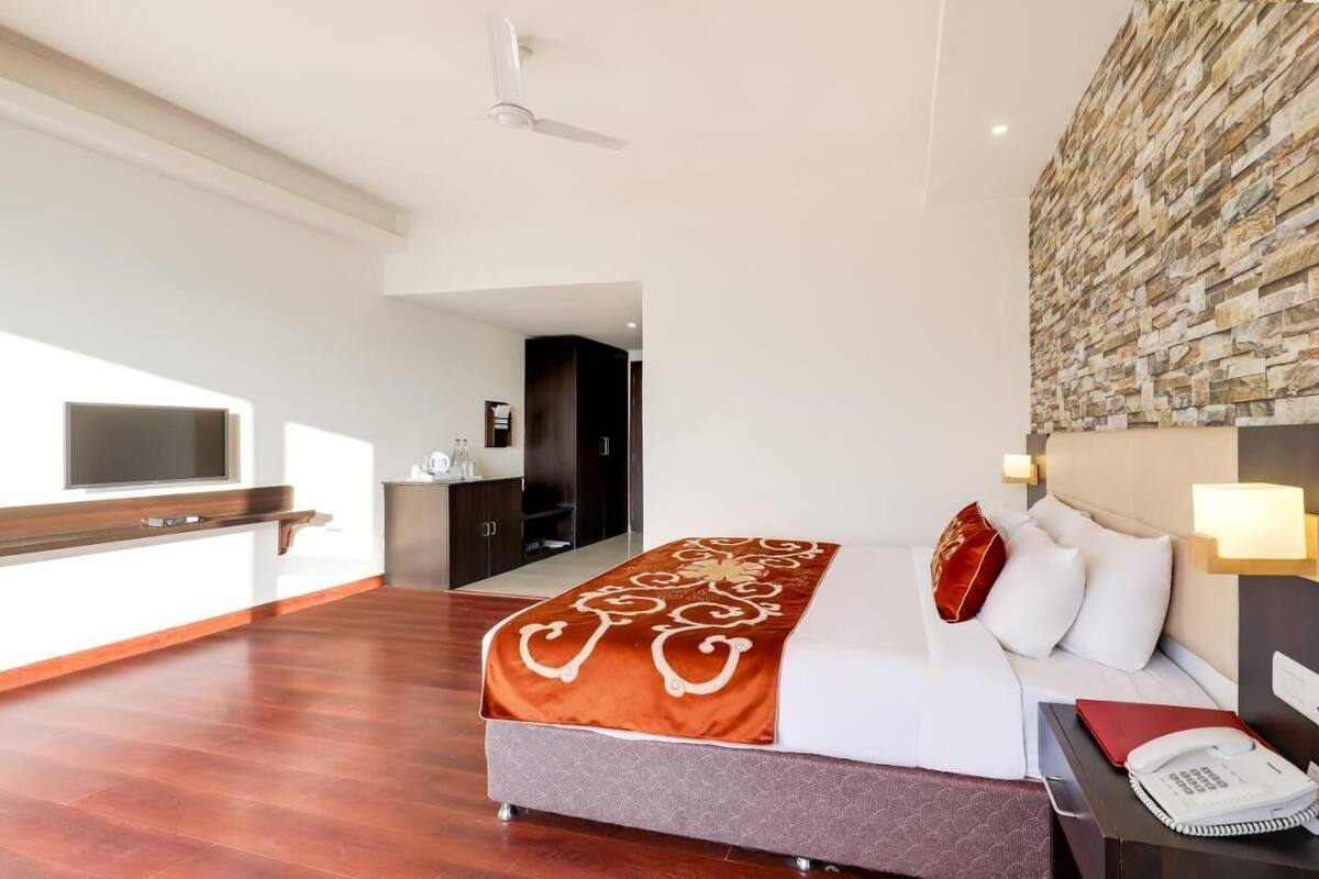 Una habitación de hotel con cama, televisión, escritorio y pared de piedra.