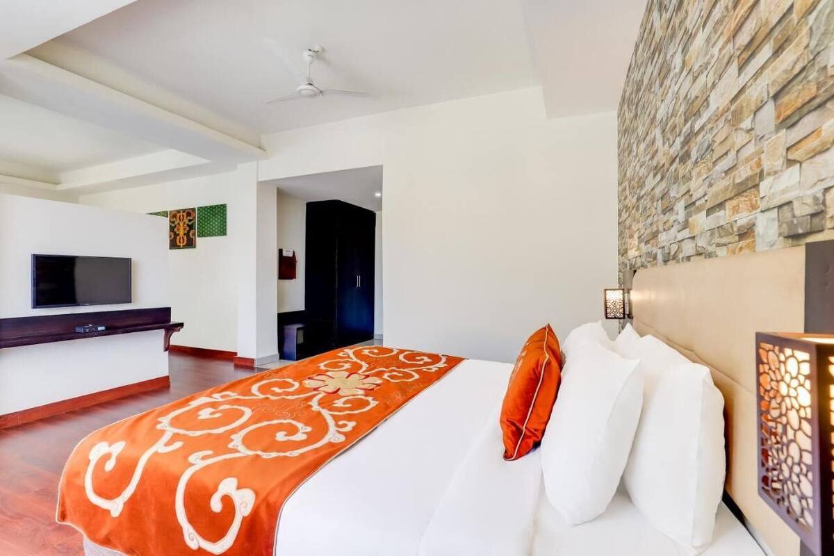 Habitación de hotel con cama, televisor de pantalla plana, escritorio y pared de piedra.