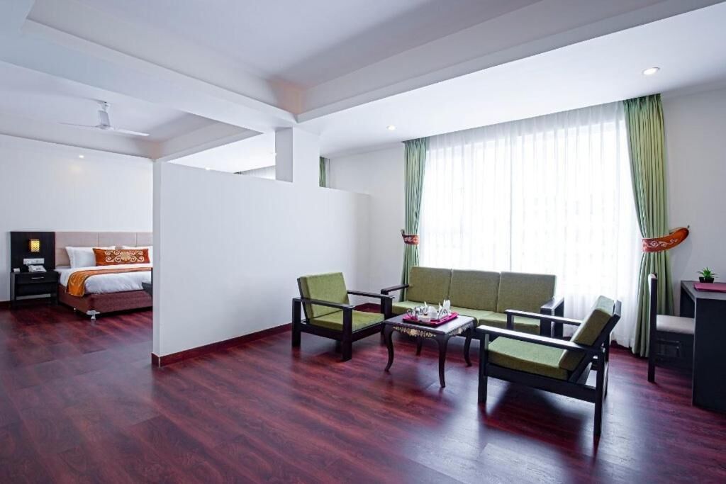Une chambre d’hôtel comprenant un lit, deux fauteuils, un canapé, une petite table et un bureau.