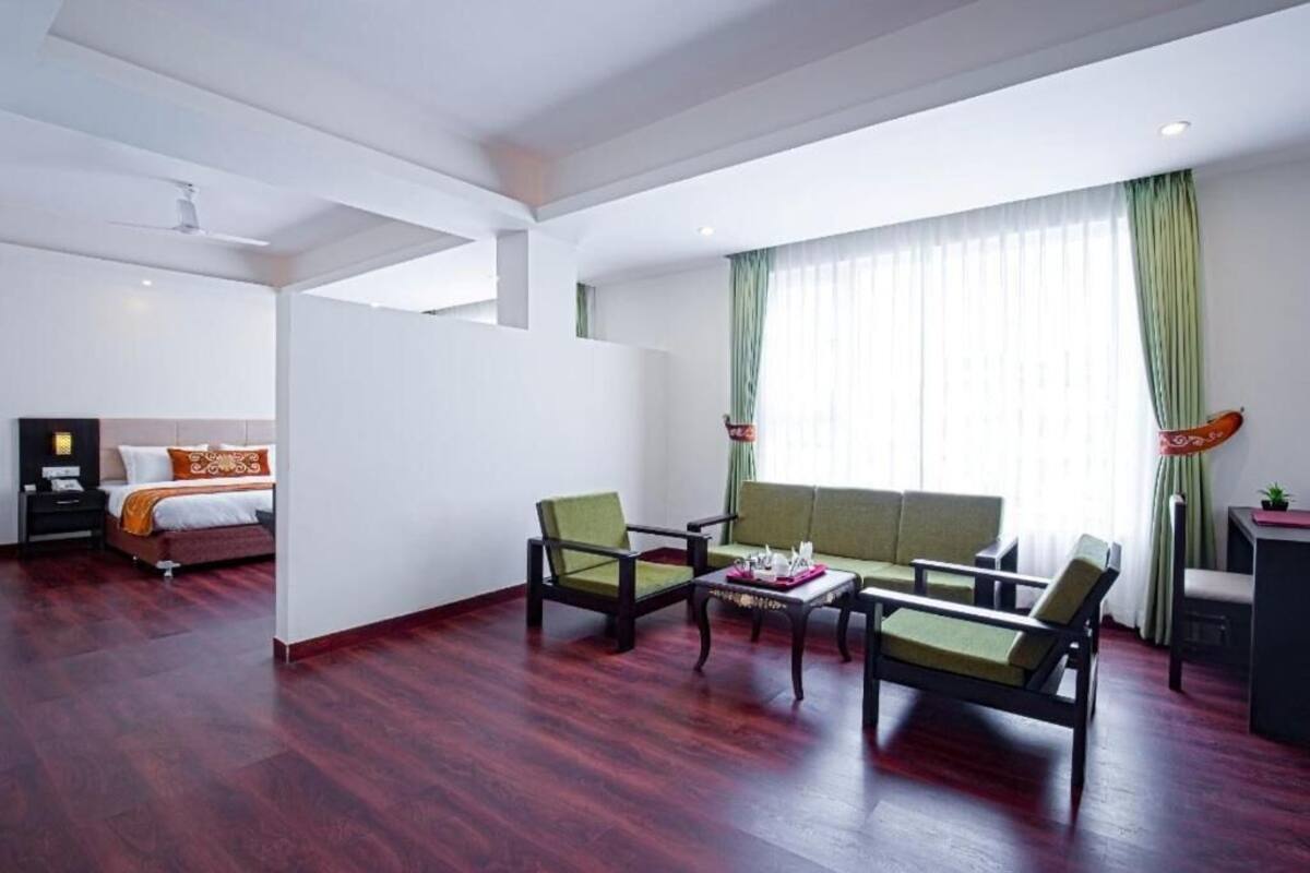 Una habitación de hotel con cama, dos sillones, un sofá, una mesita y un escritorio.