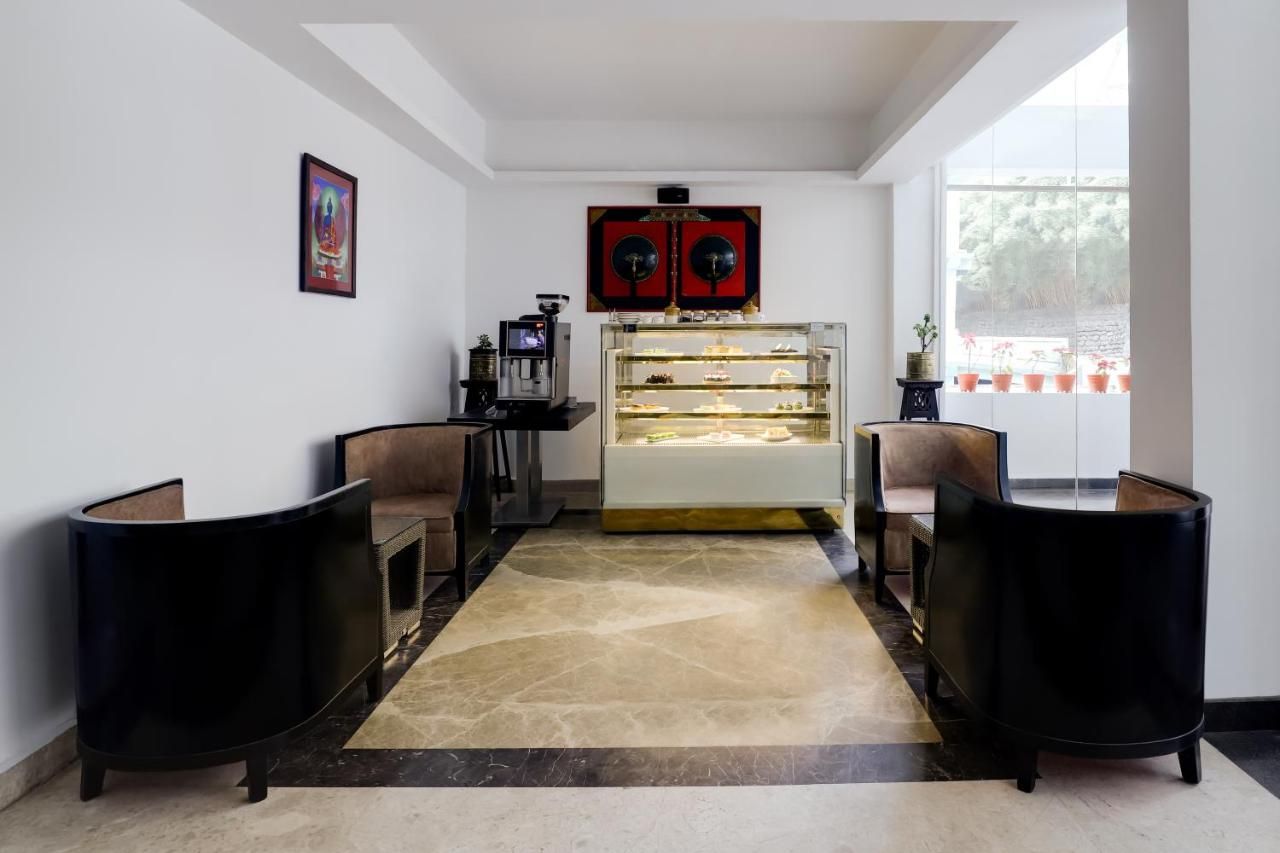 A reception area with a marble floor, two black armchairs, a glass display case, and a large window with potted plants.