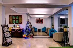 Un salon moderne avec un sapin de Noël, un coin salon et des œuvres d’art décoratives au mur.