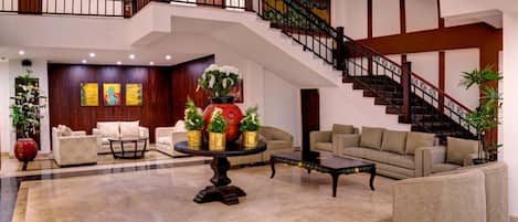 A spacious lobby with a staircase, sofas, a coffee table, and decorative vases.