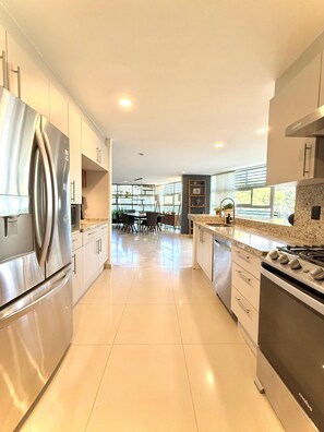 A modern kitchen with stainless steel appliances, a granite countertop, and a dining area with a table and chairs. - Penthouse with outdoor terrace in Lomas / Polanco (Ciudad de México)