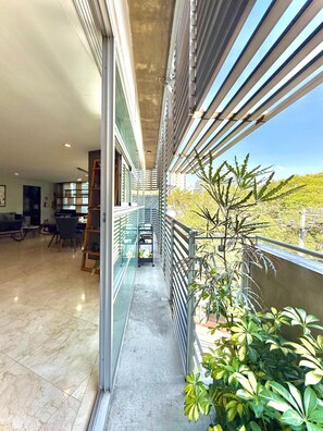 A corridor with a glass railing, leading to a balcony with plants and a view of the city. - Penthouse with outdoor terrace in Lomas / Polanco (Ciudad de México)