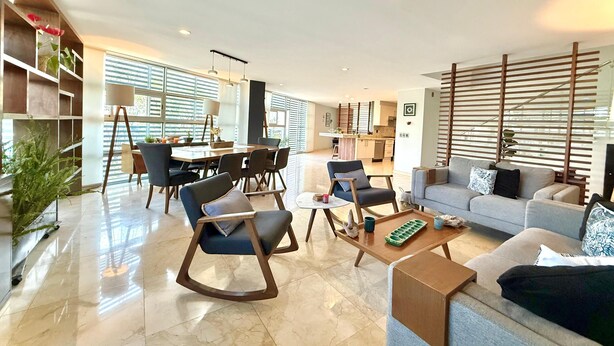 Un salon moderne comprenant un canapé, des fauteuils, une table basse et un coin repas avec une table et des chaises.