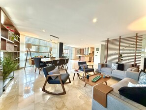 Un salon moderne comprenant un canapé, des fauteuils, une table basse et un coin repas avec une table et des chaises.