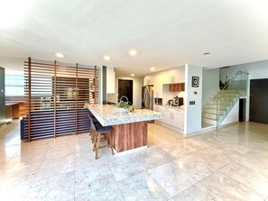 A modern kitchen with a marble countertop, stainless steel appliances, and a wooden island with bar stools. - Penthouse with outdoor terrace in Lomas / Polanco (Ciudad de México)