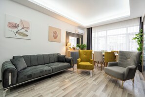 Ein modernes Wohnzimmer mit Sofa, Sessel und Essbereich.
