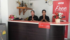 Un mostrador de recepción con un reloj, una estatua de Buda y un cartel que ofrece la siguiente reserva gratuita.