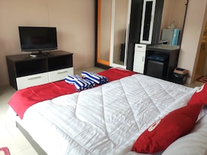 A hotel room with a bed, a TV on a black cabinet, a wardrobe, and a mirror. - Oyo 75414 Kjs Pattaya (Pattaya)