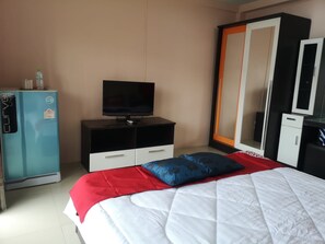 Een hotelkamer met een bed, televisie, kast en minibar.