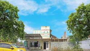 A building with a large sign, a yellow car parked in front, and trees around. - Oyo 91766 Fortuna Hotel Syariah (Banyumas)