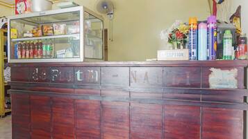 A reception desk with a glass display case containing snacks and beverages, a fan, and a 'RECEPTION' sign.