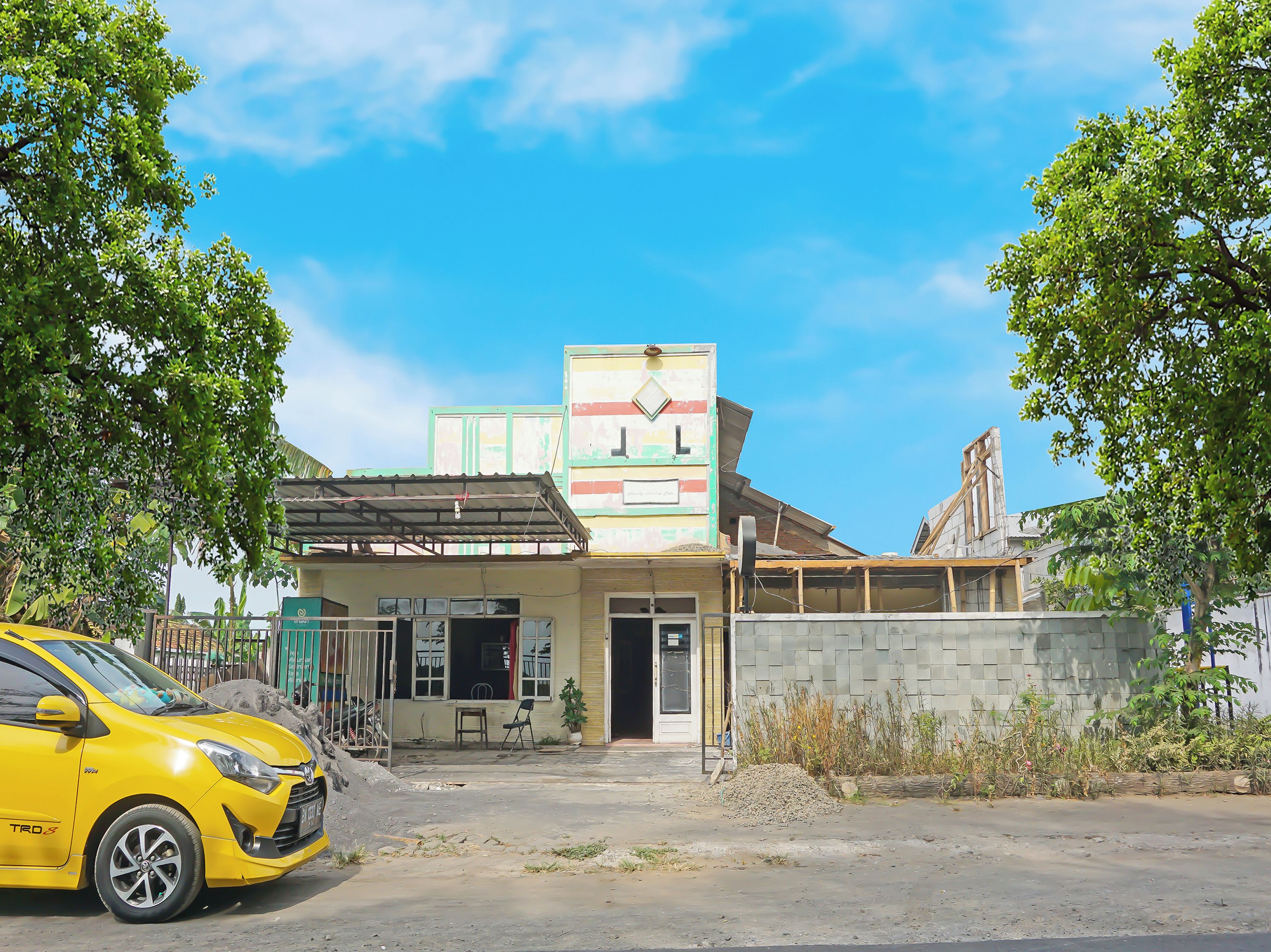 A building with a signboard, a parked car, and a clear sky.