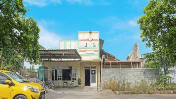 A building with a signboard, a parked car, and a clear sky.