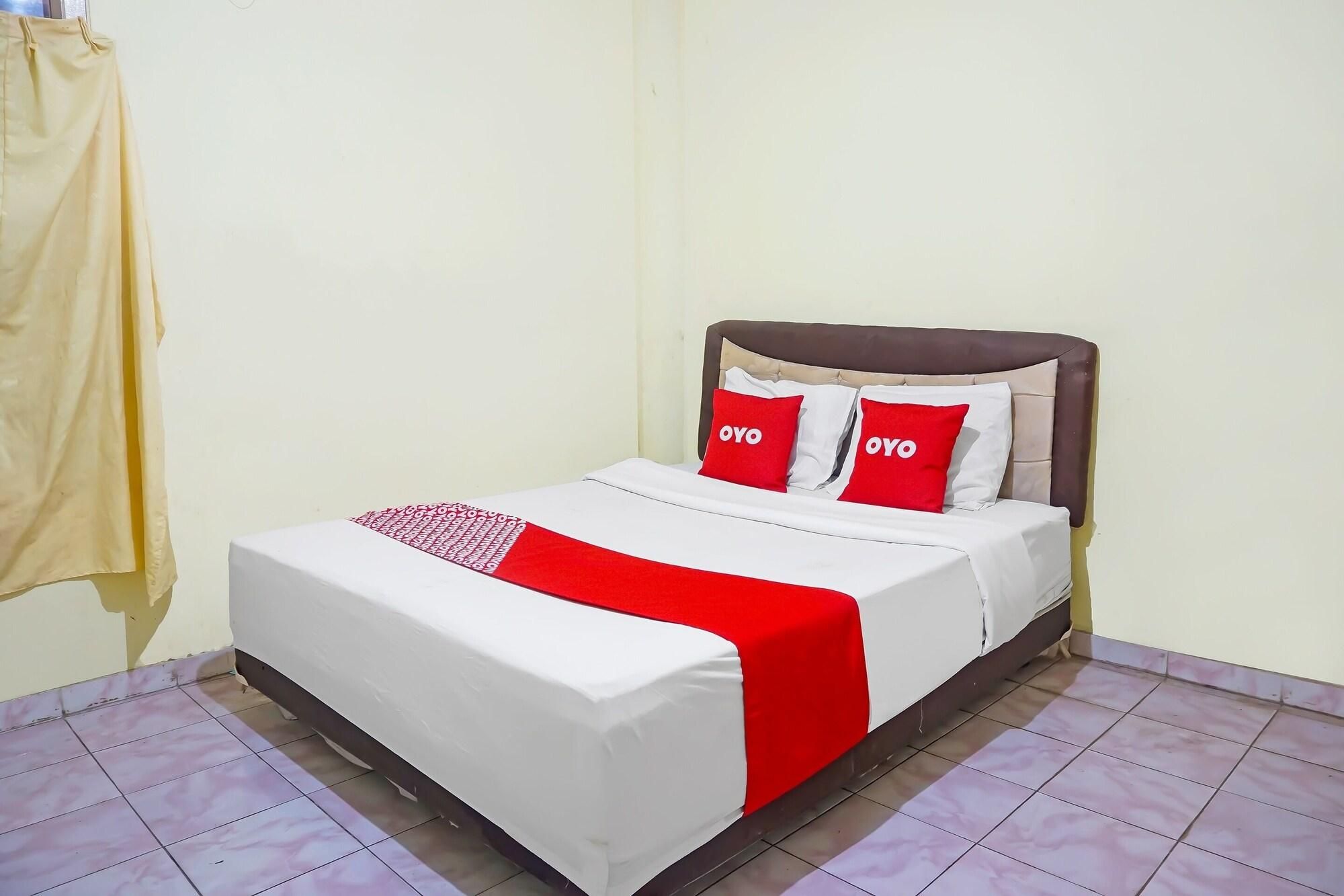 A bed with a white and red bedspread, two red pillows with 'OYO' text, and a brown headboard.