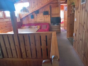 Interno di una baita in legno con divano, tavolo e televisore.