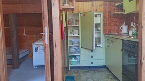 A compact kitchen with a built-in oven, a small refrigerator, and a wooden cabinet. - Haus Vernier, (Seewis). by Interhome (Seewis im Prättigau)