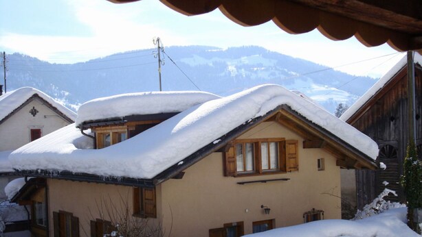 A snow-covered chalet with a sloped roof, wooden shutters, and a mountain backdrop. - Haus Vernier, (Seewis). by Interhome (Seewis im Prättigau)