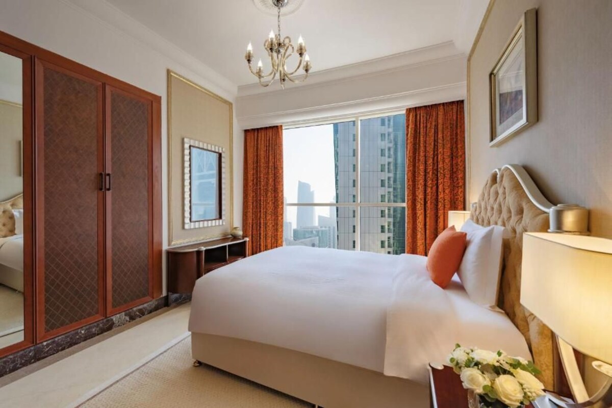 A hotel room with a large bed, a wardrobe, a desk, and a view of the city.