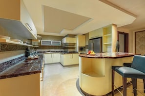 A modern kitchen with a curved island, built-in appliances, and a bar area. - Dusit Hotel and Suites Doha (Doha)
