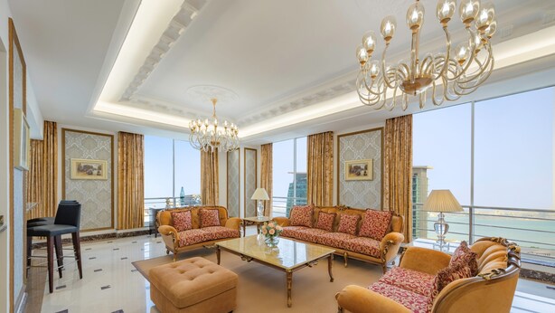 A spacious living room with a chandelier, sofas, ottoman, and a coffee table. - Dusit Hotel and Suites Doha (Doha)
