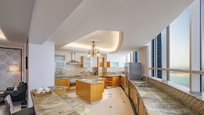 A modern kitchen with a central island, built-in appliances, and large windows offering a view. - Dusit Hotel and Suites Doha (Doha)