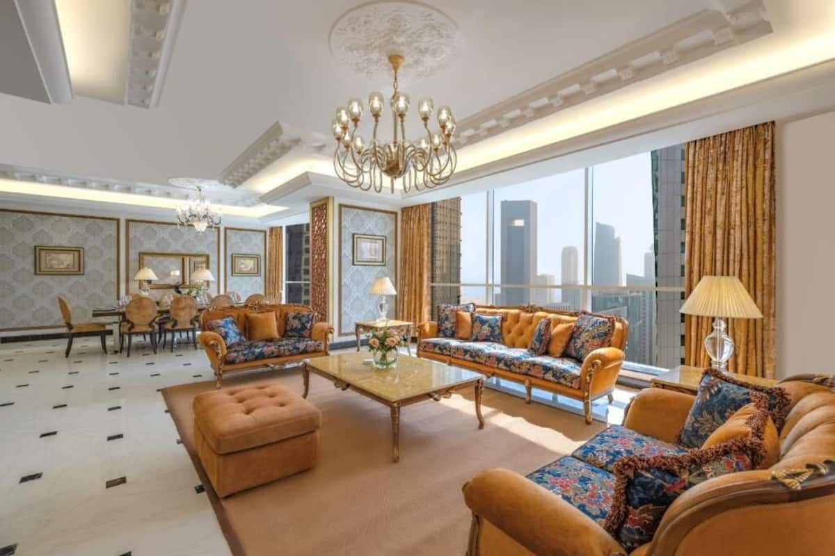 Ein geräumiges Wohnzimmer mit großem Fenster, einer Chandelierleuchtre und einem Essbereich mit Tisch und Stühlen.