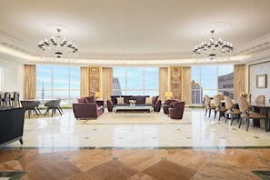 A spacious hotel lobby with a large seating area, chandeliers, and large windows offering a city view. - Dusit Hotel and Suites Doha (Doha)