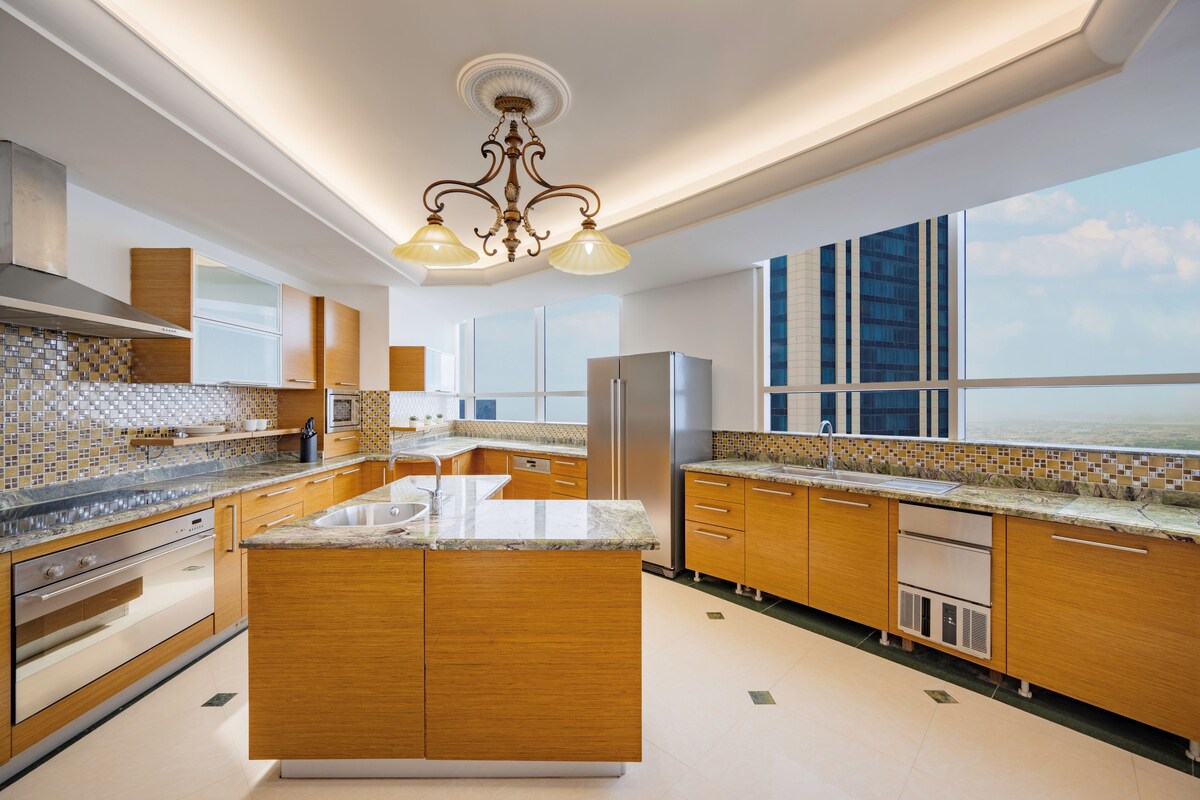 A modern kitchen with a central island, stainless steel appliances, and a large window offering a view.
