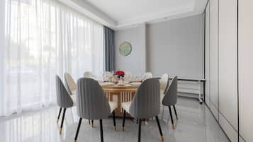 Un comedor moderno con una mesa redonda, seis sillas y un florero con flores rojas.