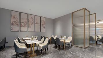 Un comedor moderno con suelo de mármol, sillas grises y blancas, y obras de arte tradicionales en las paredes.