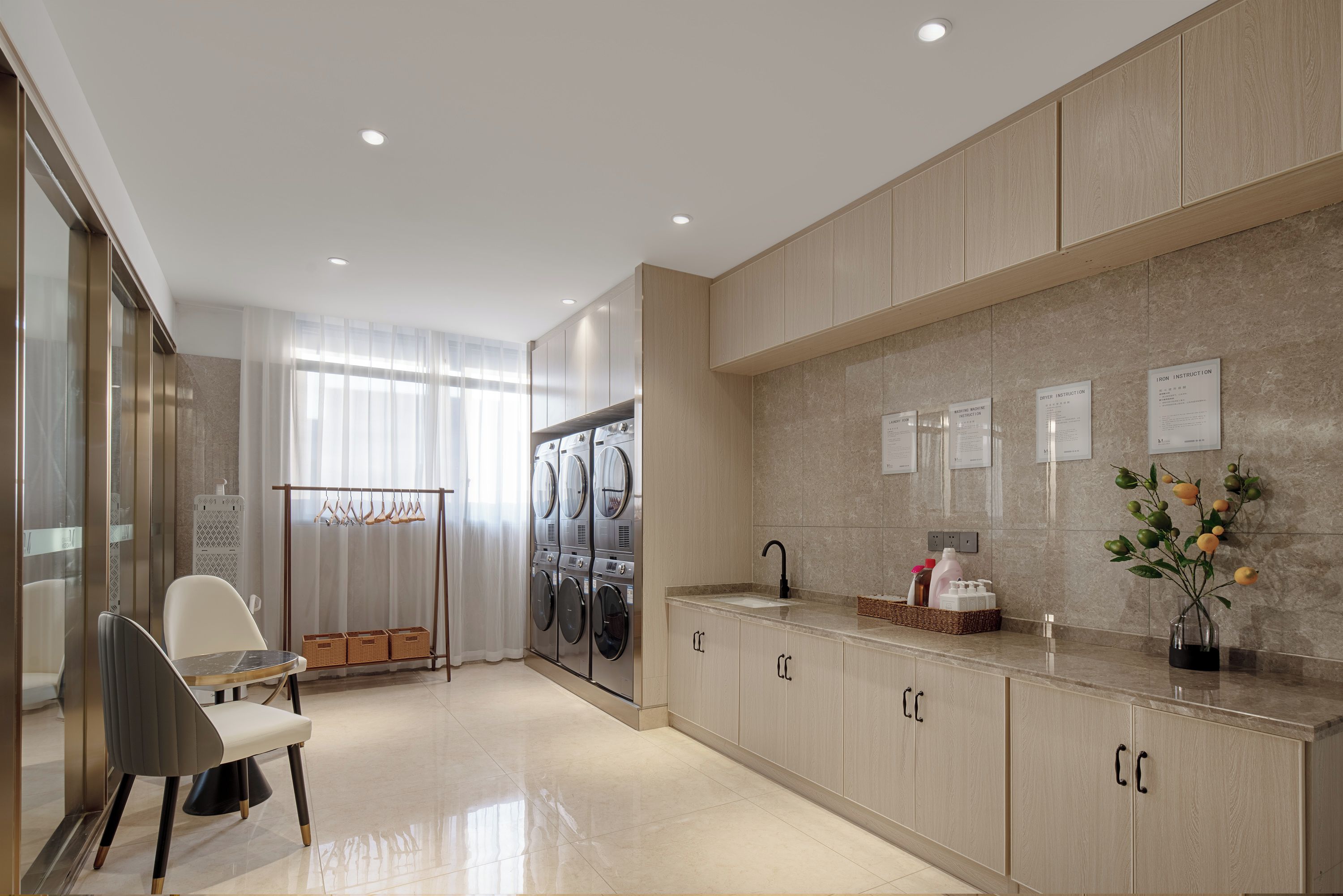 A modern kitchen with a built-in washer and dryer, a dining area with a table and chairs, and a countertop with a sink and decorative items.