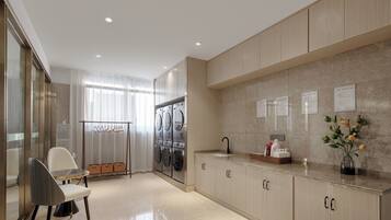 A modern kitchen with a built-in washer and dryer, a dining area with a table and chairs, and a countertop with a sink and decorative items.