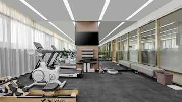 Academia moderna com bicicletas ergométricas, esteiras e remo.
