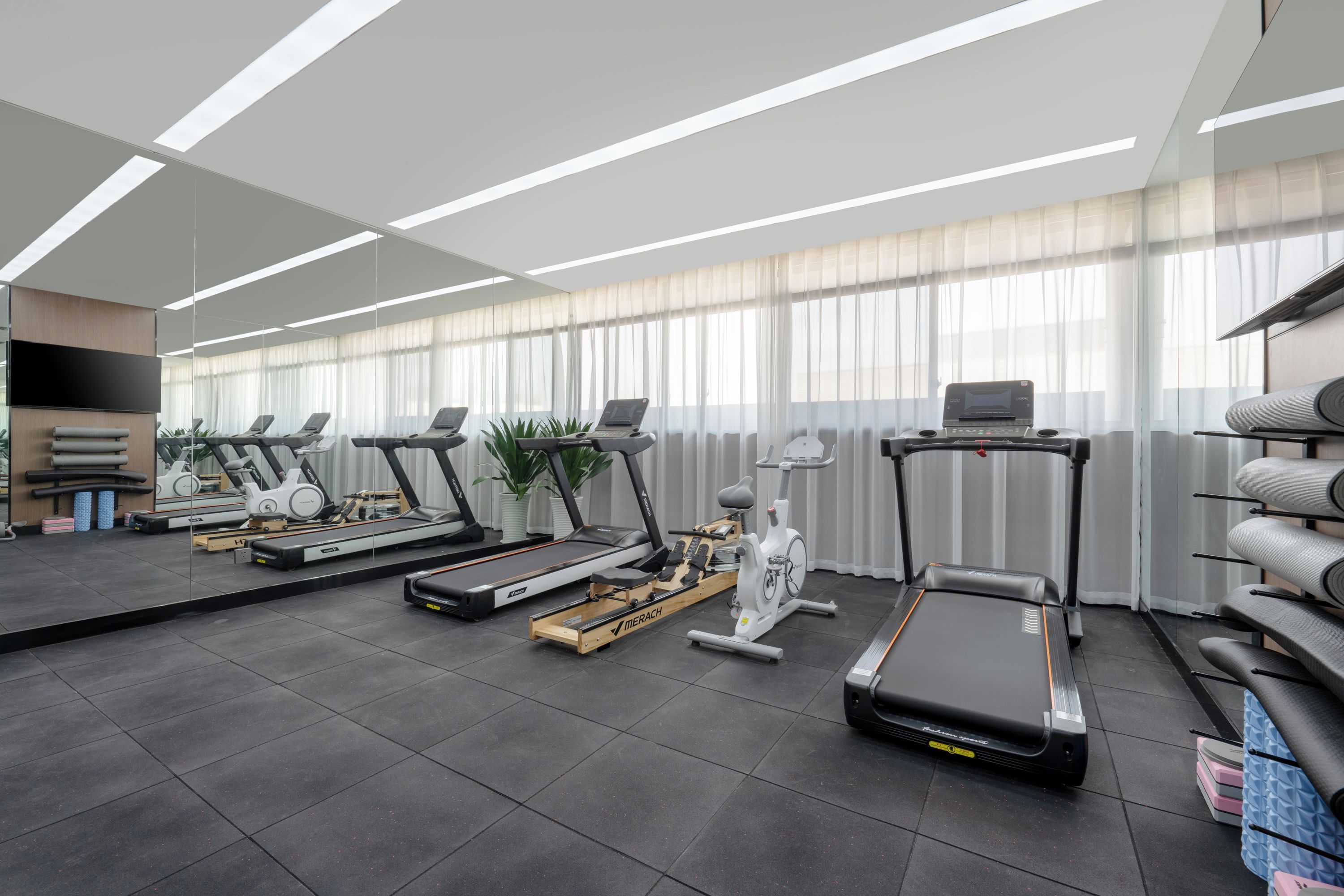 A modern gym with treadmills, stationary bikes, and rowing machines.