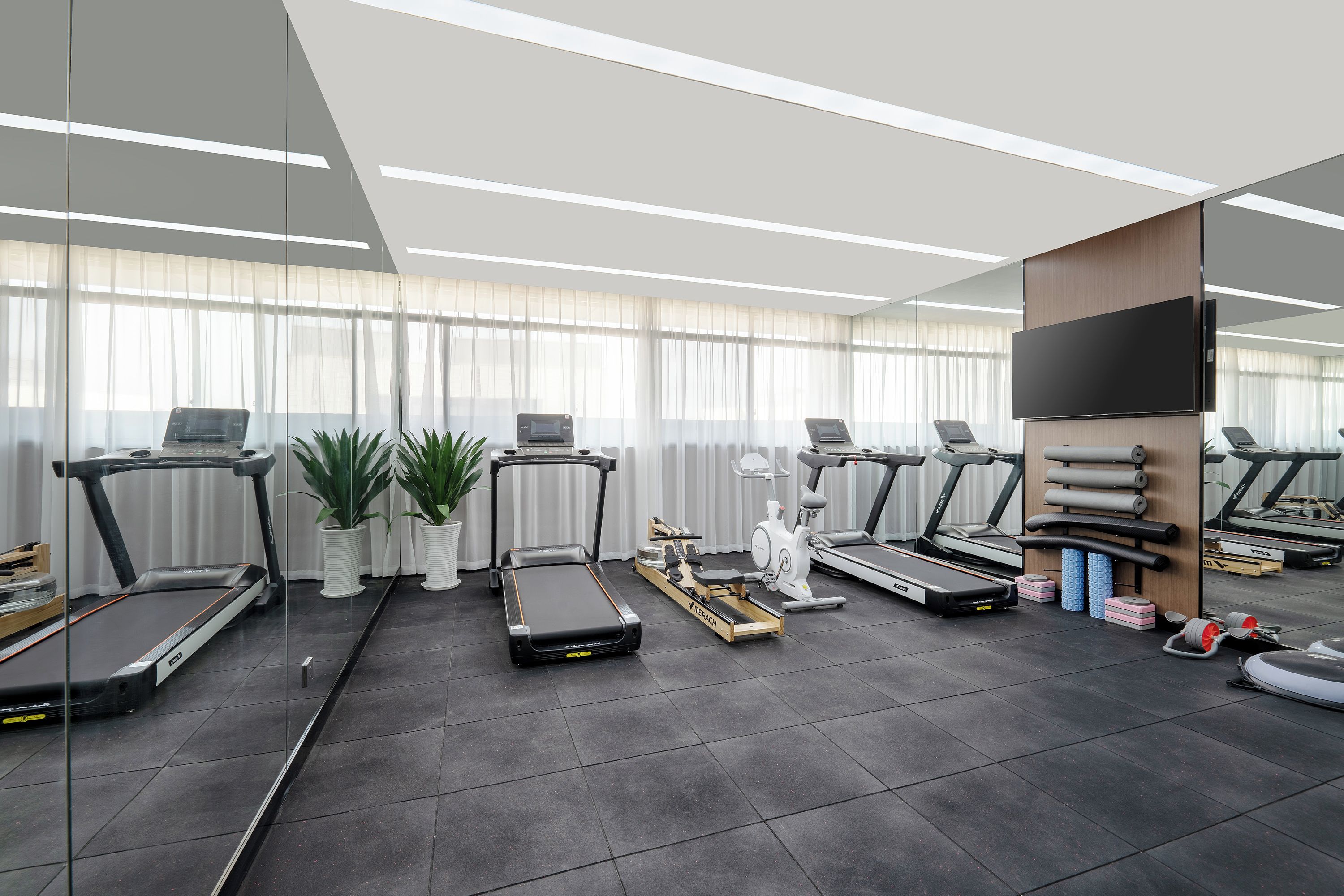 A modern gym with multiple treadmills, stationary bikes, and a rowing machine.