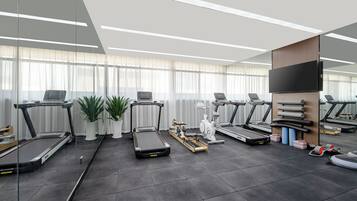 A modern gym with multiple treadmills, stationary bikes, and a rowing machine.