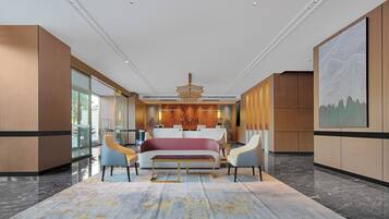 Un moderno vestíbulo de hotel con una cama grande, zona de estar y un mostrador de recepción.