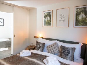 Ein Schlafzimmer mit einem Bett, Kissen, einem Nachttisch und gerahmten Bildern an der Wand.