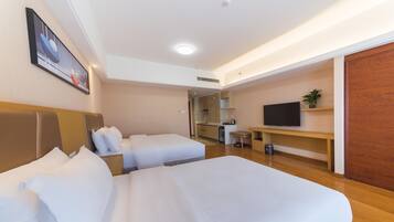 A hotel room with two beds, a TV, a small kitchenette, and a wooden floor.