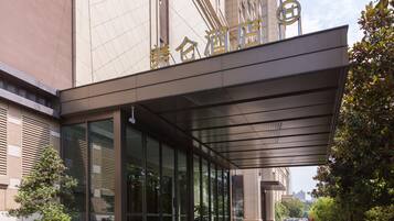 A modern building with a large glass entrance, a covered walkway, and a sign with Chinese characters.