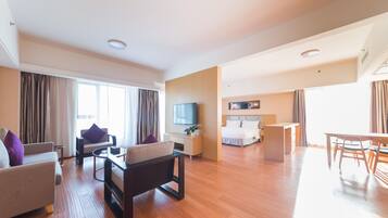 Una habitación de hotel moderna con sala de estar, dormitorio independiente, comedor y televisor.