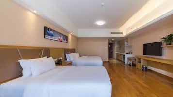 Habitación de hotel con dos camas, un televisor, un escritorio y un cuadro en la pared.