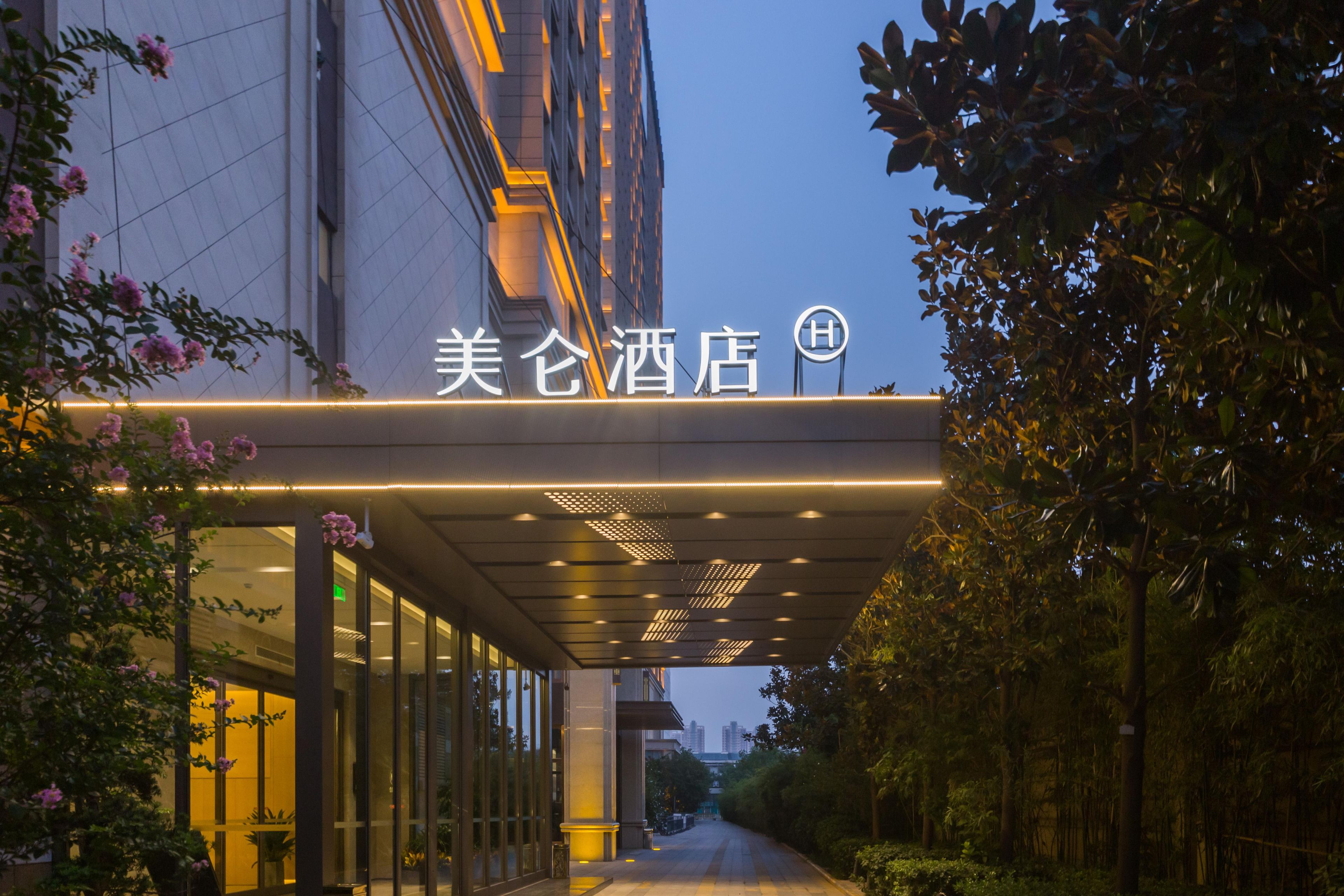 A hotel entrance with a covered walkway, glass doors, and a sign with Chinese characters.