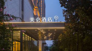 A hotel entrance with a covered walkway, glass doors, and a sign with Chinese characters.