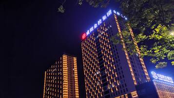 Dos edificios de gran altura con señalización iluminada, uno con un logotipo circular rojo y el otro con uno azul.