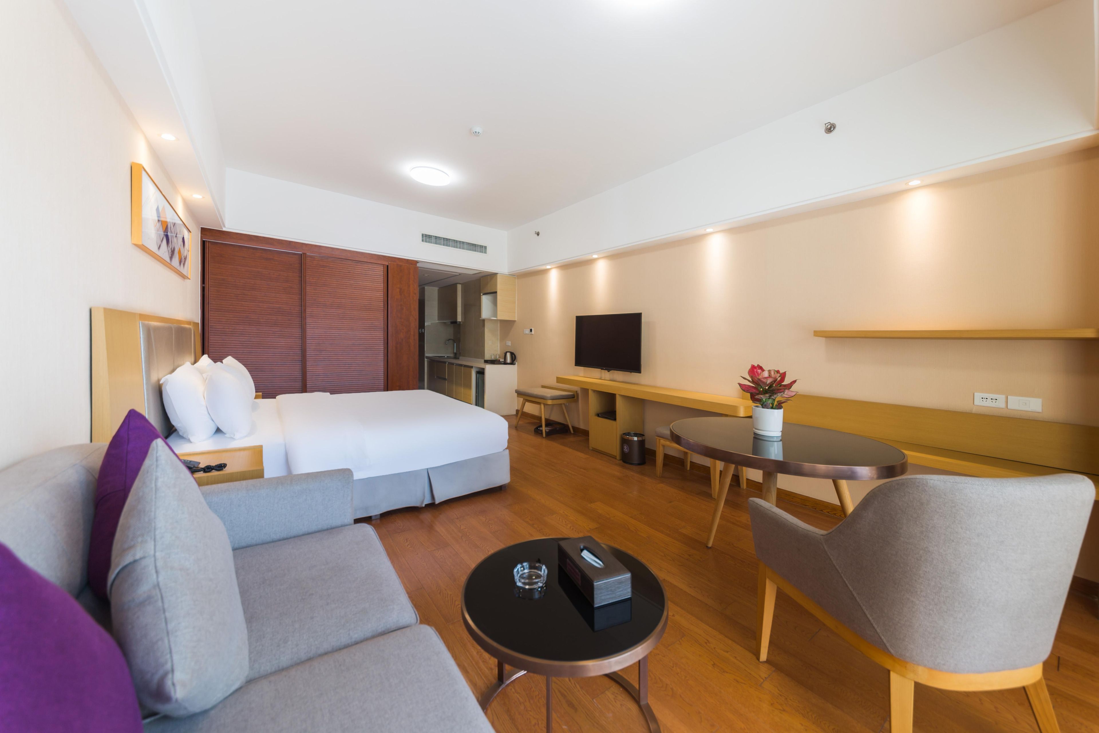 Ein Hotelzimmer mit Bett, Sofa, Esstisch, Fernseher und Küchenzeile.