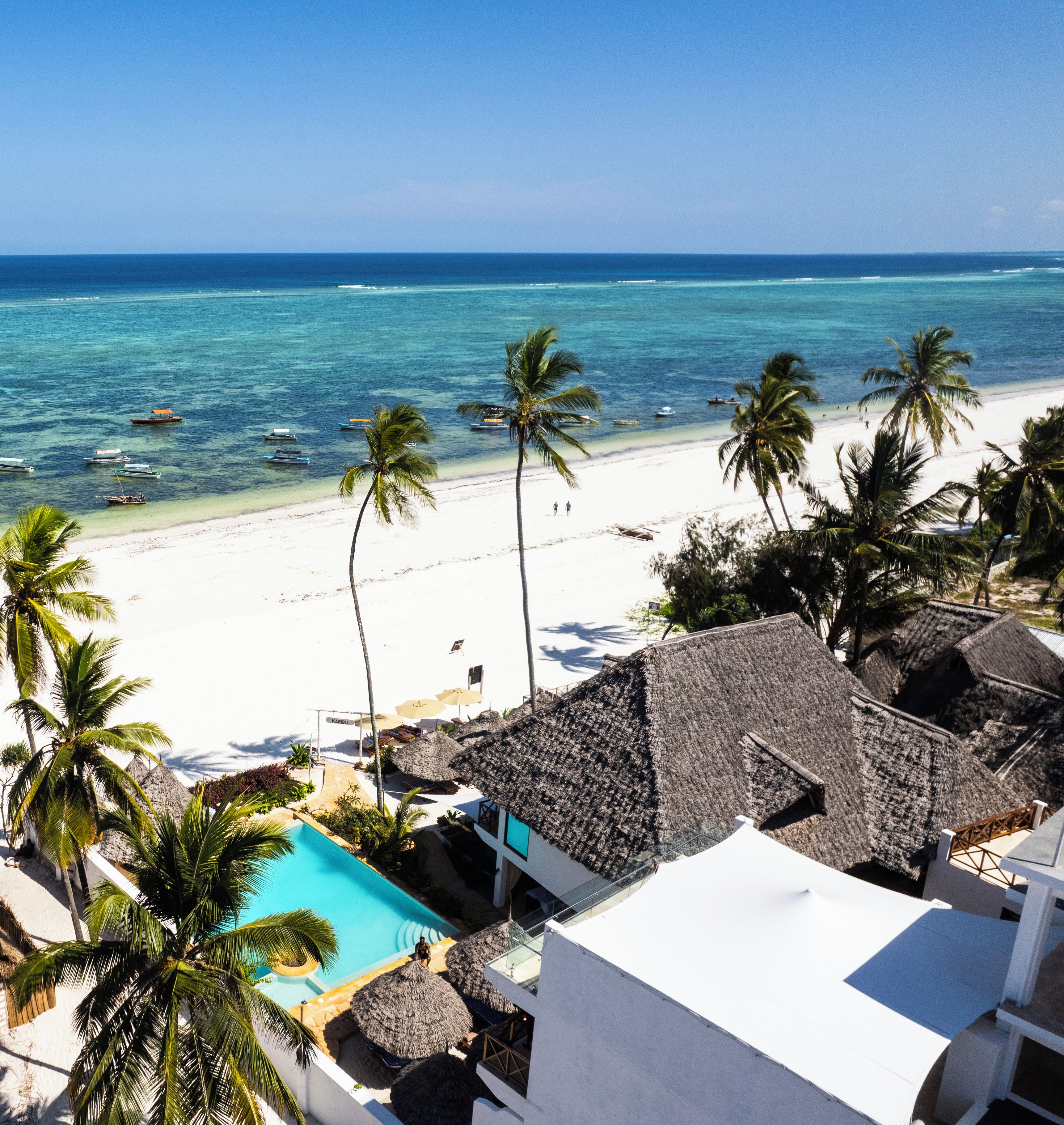 Un resort sulla spiaggia con piscina, palme e vista sull'oceano.